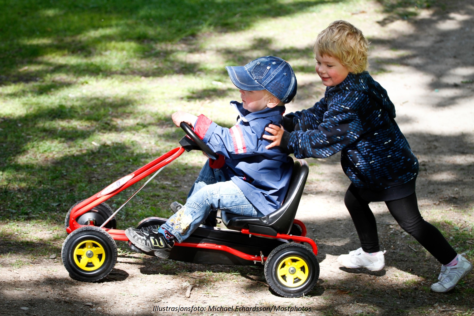 Omslagsfoto. To barn i femårsalderen som leker med en tråbil.