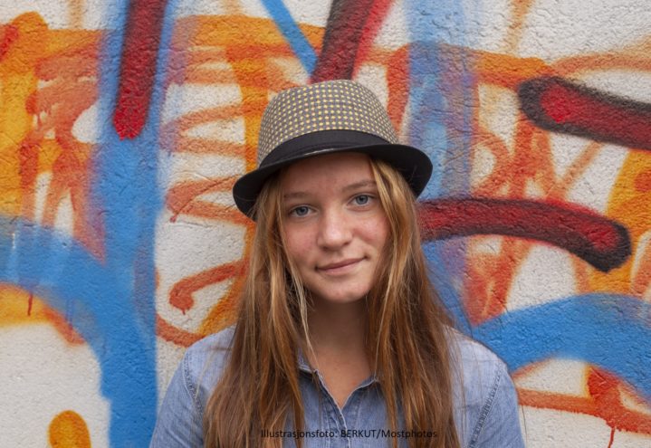 Teenager standing against a wall with graffiti