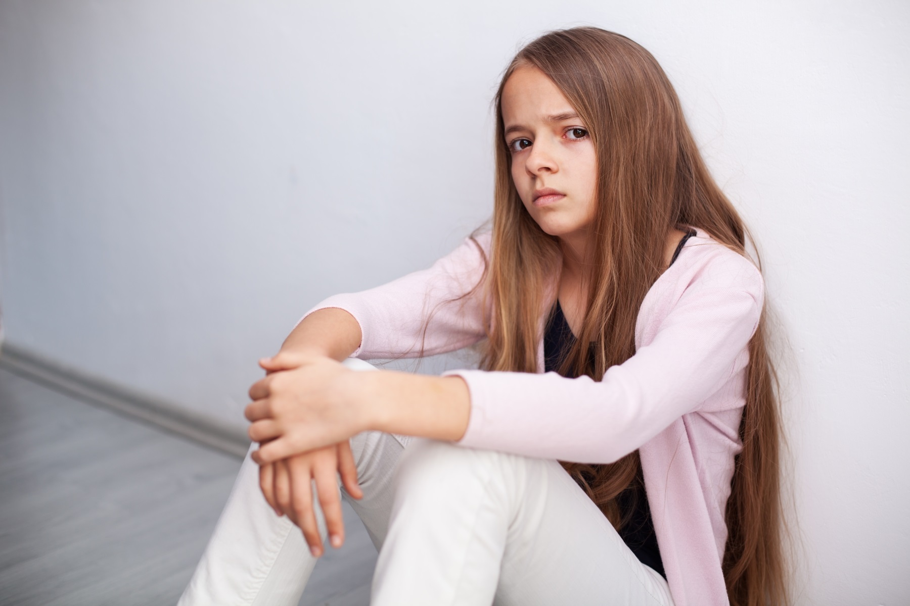 Illustration photo. Girl sitting on the floor looking anxious.