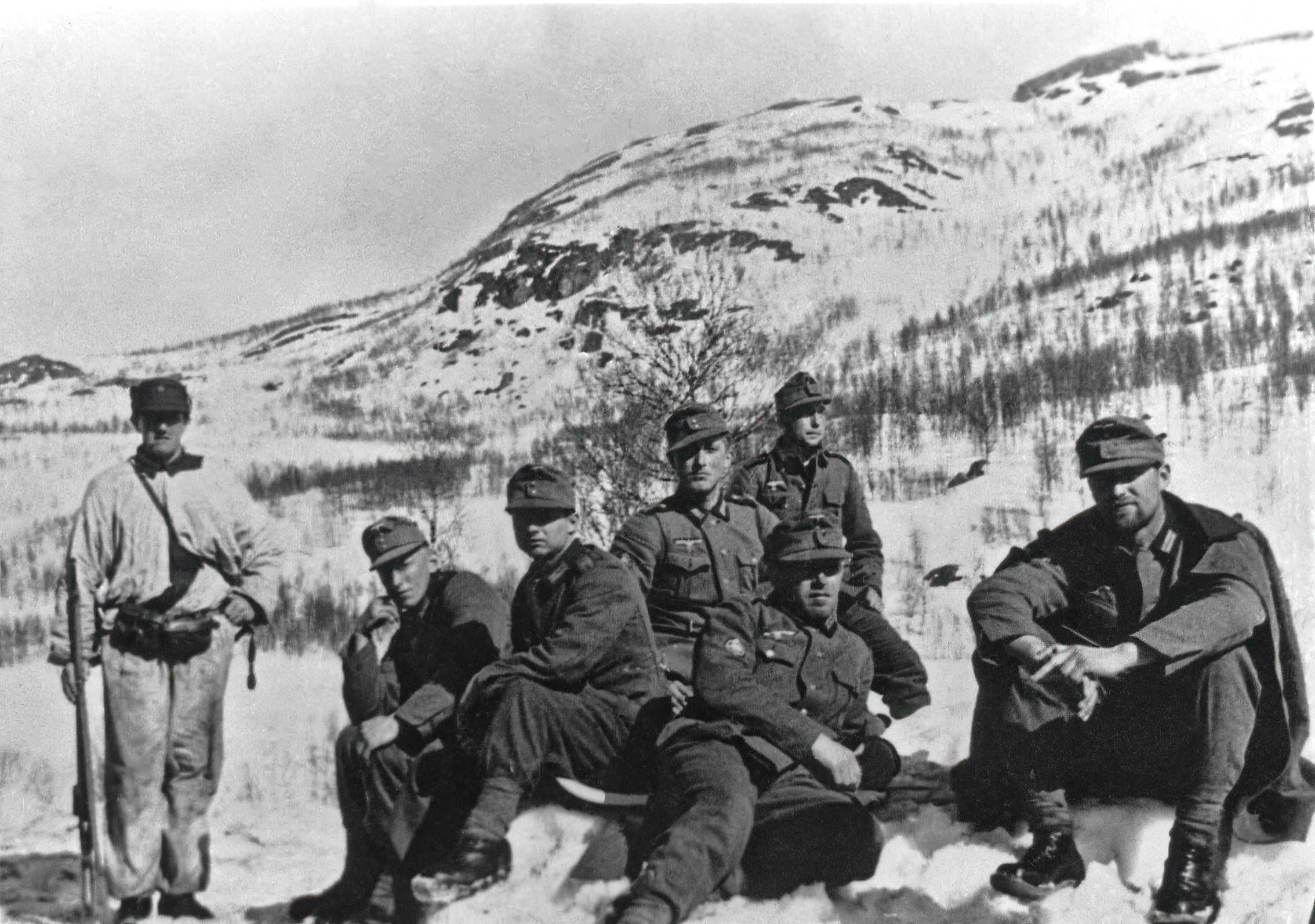 En gruppe soldater sitter på snødekt mark.